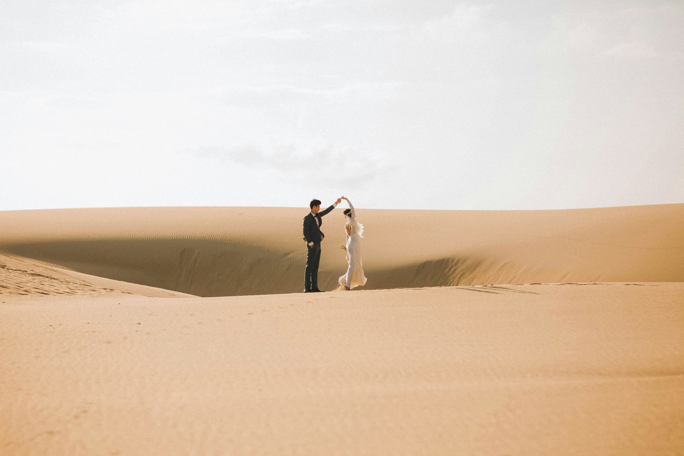A couple dancing alone in the desert dunes